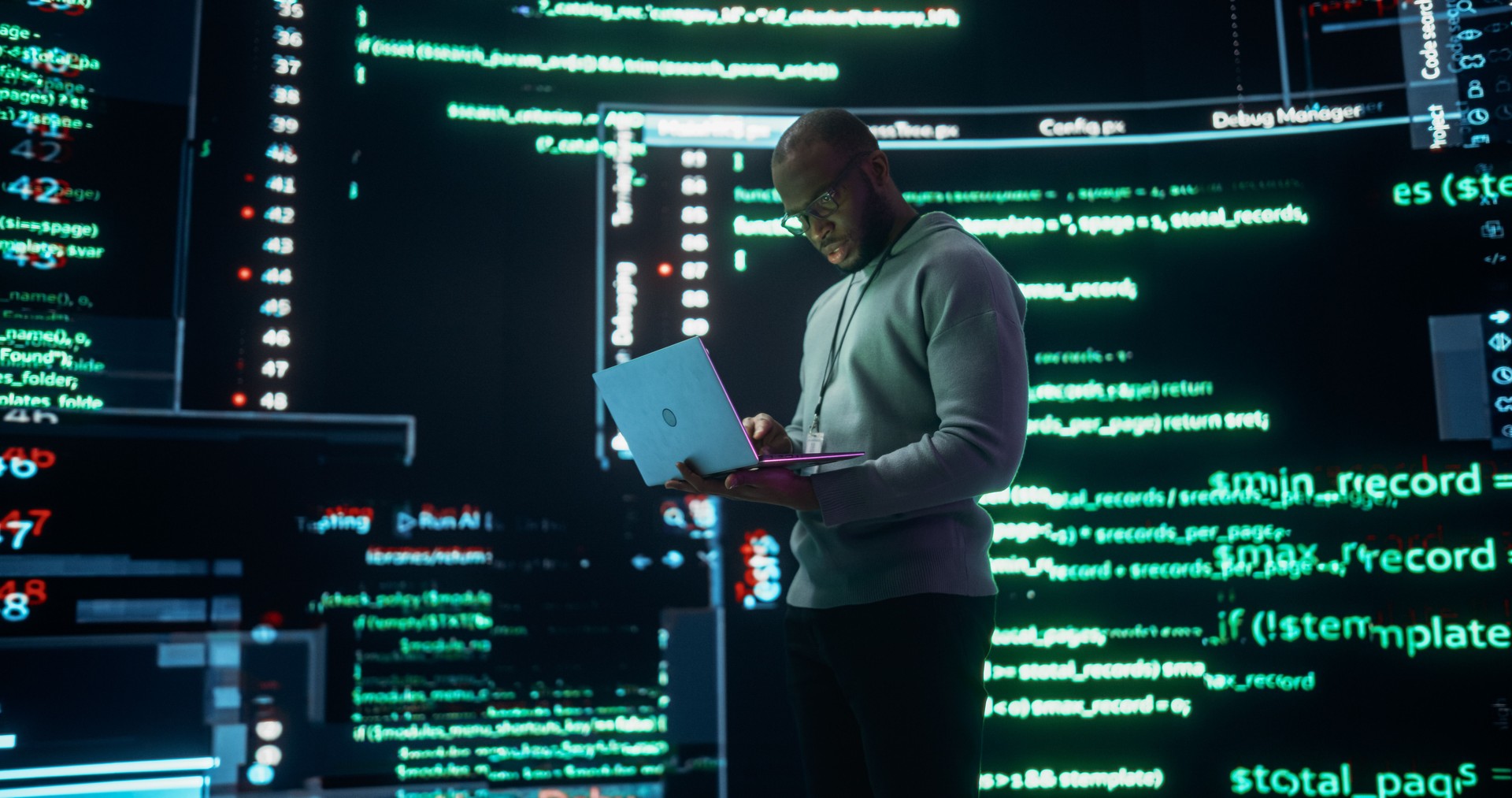 Portrait of Young Black Man Working on Laptop Computer, Looking at Big Digital Screens Glitching While Displaying Code Lines. Professional Programmer Fixing a Bug, Dealing with Crashing System